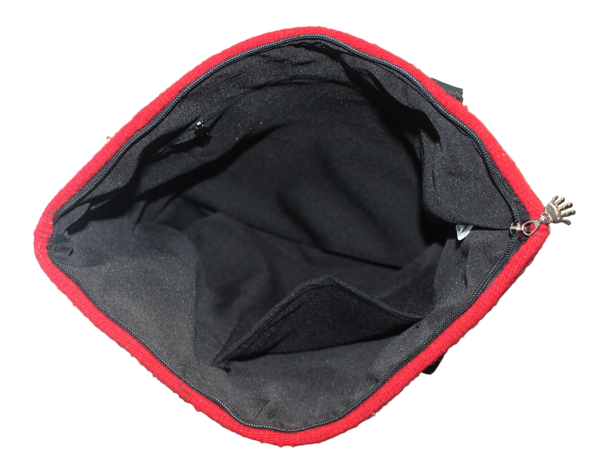 An open black zippered pouch or small bag with a bright red fabric trim, photographed from above on a gray carpeted floor.